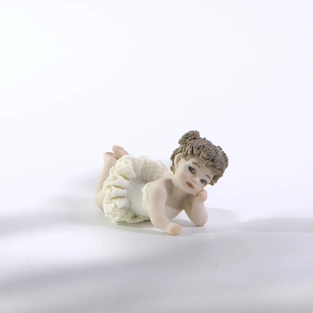Statua in porcellana Ada Petipa, bimba ballerina in tutù di pizzo stesa a terra sulla pancia con due codine alte.