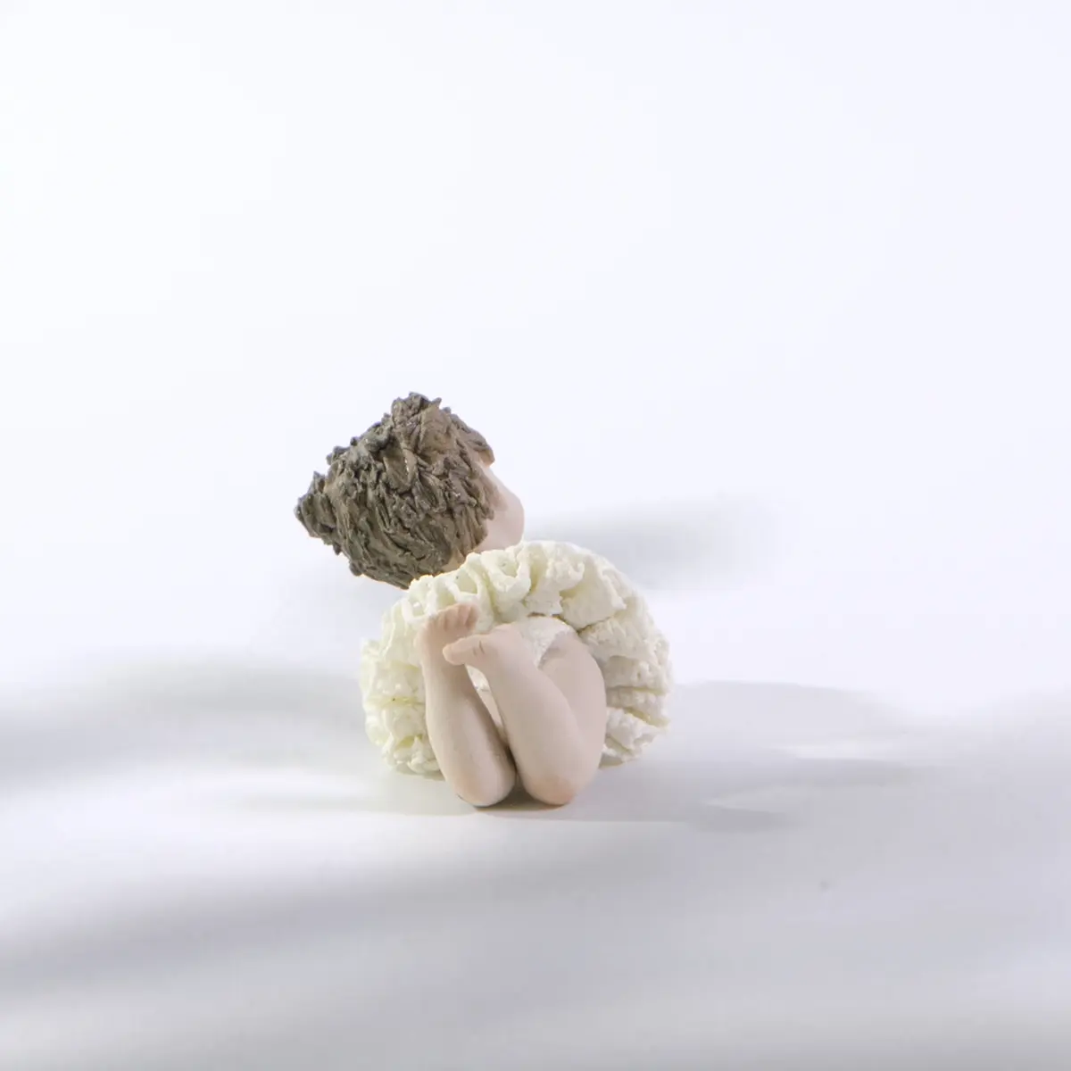 Statua in porcellana Ada Petipa, bimba ballerina in tutù di pizzo stesa a terra sulla pancia con due codine alte.