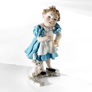 Statua in porcellana di Alice con abito azzurro, grembiule bianco e coniglietto ai piedi.