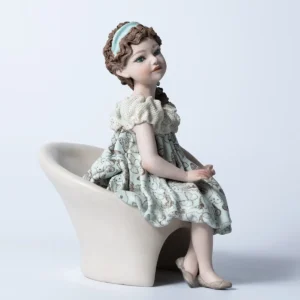 Statua in porcellana di ragazza seduta su poltrona bianca con abito azzurro acquamarina e decoro di farfalle.
