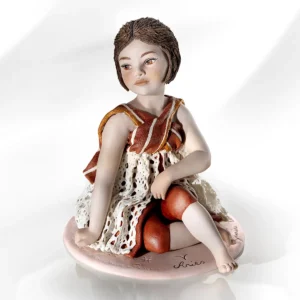Statua in porcellana Ariete di Sibania con mantello, pizzo rosso, dettagli dorati e base rossa.