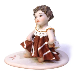 Statuetta in porcellana mini Ariete di Sibania con abito rosso in pizzo, profili dorati e mantello su base rossa.