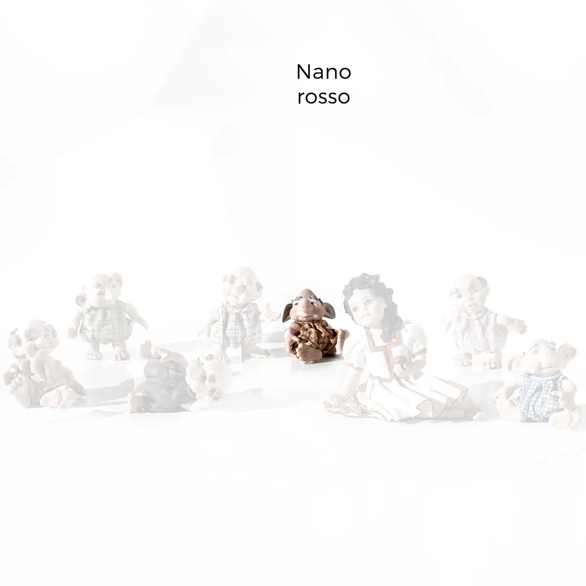 Statua in porcellana del Nano Rosso con capelli bianchi, seduto a terra mentre si guarda attorno confuso.