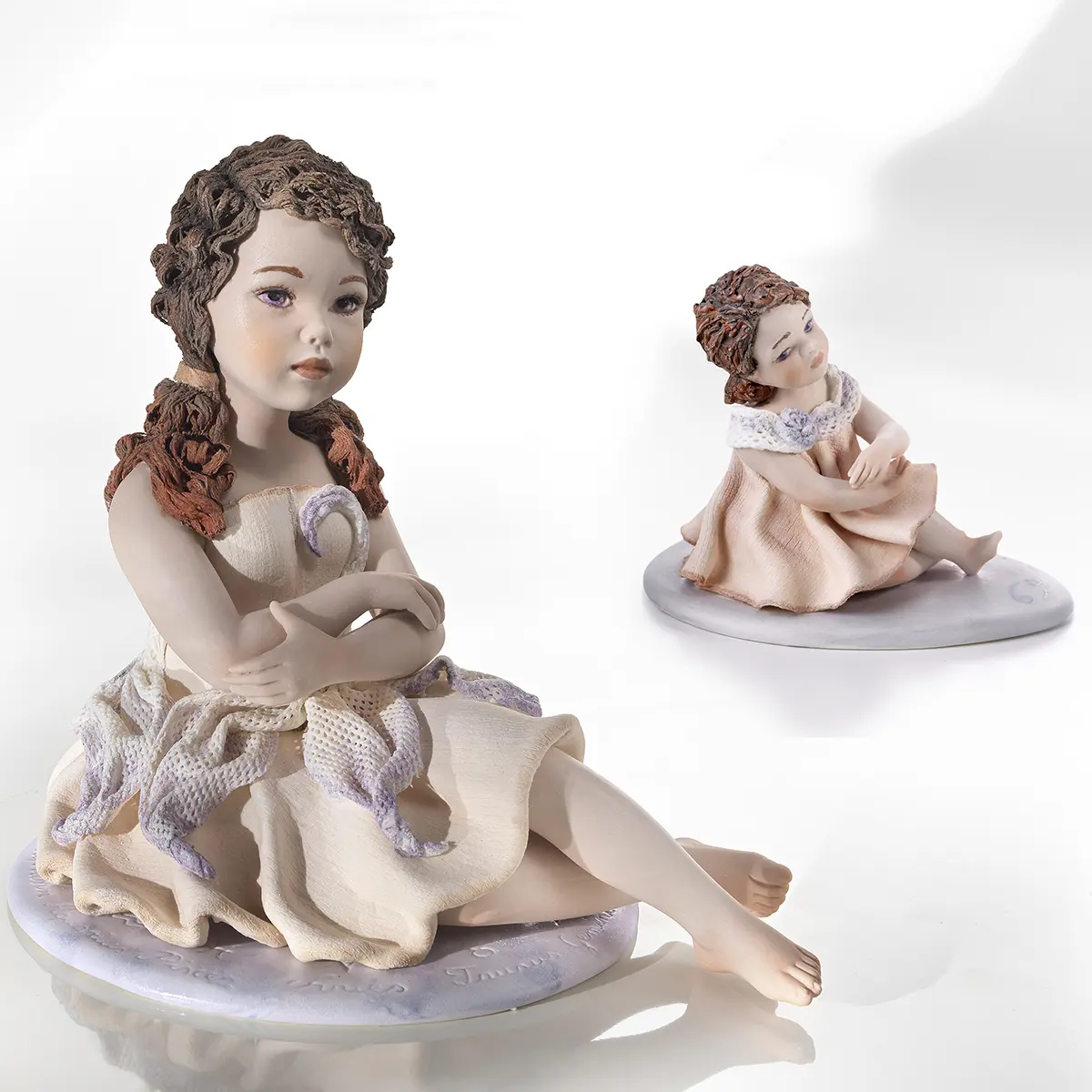 Statue in porcellana Sibania del segno Cancro e mini Cancro in abiti bianco e rosa tenue.
