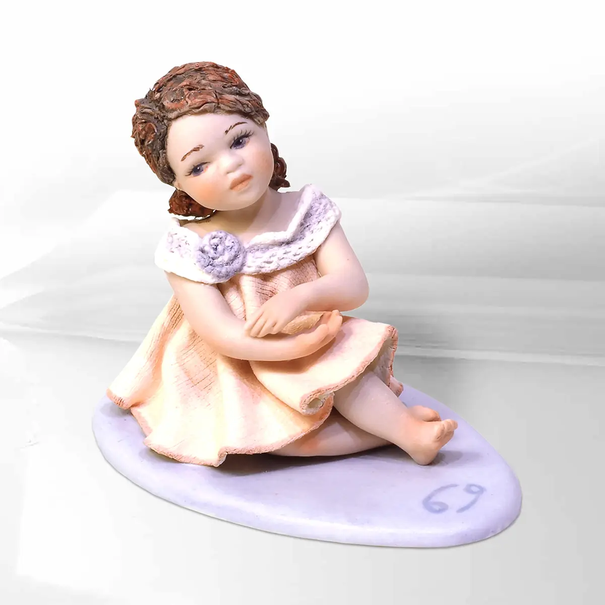 Statua mini Cancro di Sibania in abito bianco e rosa tenue con dettagli in tulle, code rosse e base viola.
