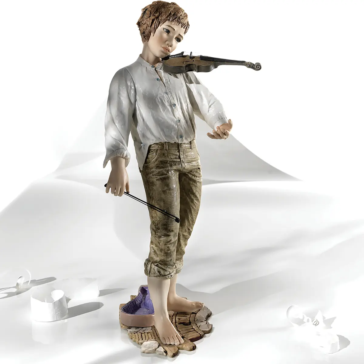 Statua in porcellana di ragazzo con violino, camicia bianca e pantaloni verde senape davanti alla custodia.
