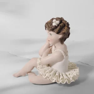 Statua in porcellana di bimba ballerina in tutù di pizzo, seduta a terra col viso su una mano e fiocchetto nei capelli.