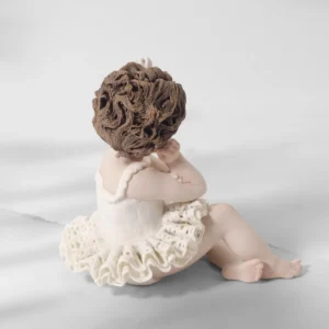 Statua in porcellana di bimba ballerina in tutù di pizzo, seduta a terra col viso su una mano e fiocco nei capelli corti.