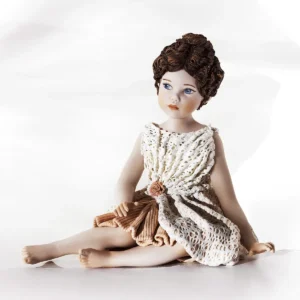 Statua in porcellana di ragazza seduta con abito in pizzo rosa e bianco e capelli raccolti in un morbido chignon.