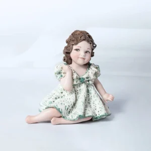 Statua in porcellana di bimba in abito di pizzo bianco e verde con fiocco sul petto e chignon ai lati del collo.