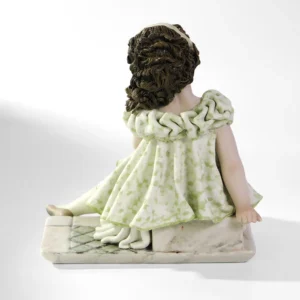Statua in porcellana di ragazza in abito verde pastello seduta su uno scalino marmorizzato.