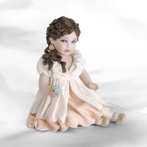 Statua in porcellana di ragazza seduta con abito in tulle, sottogonna rosa, bavero vaporoso e fiorellini colorati.