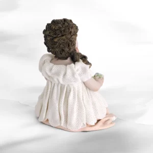 Statua in porcellana di ragazza seduta con abito in tulle, sottogonna rosa e fiorellini colorati in mano.