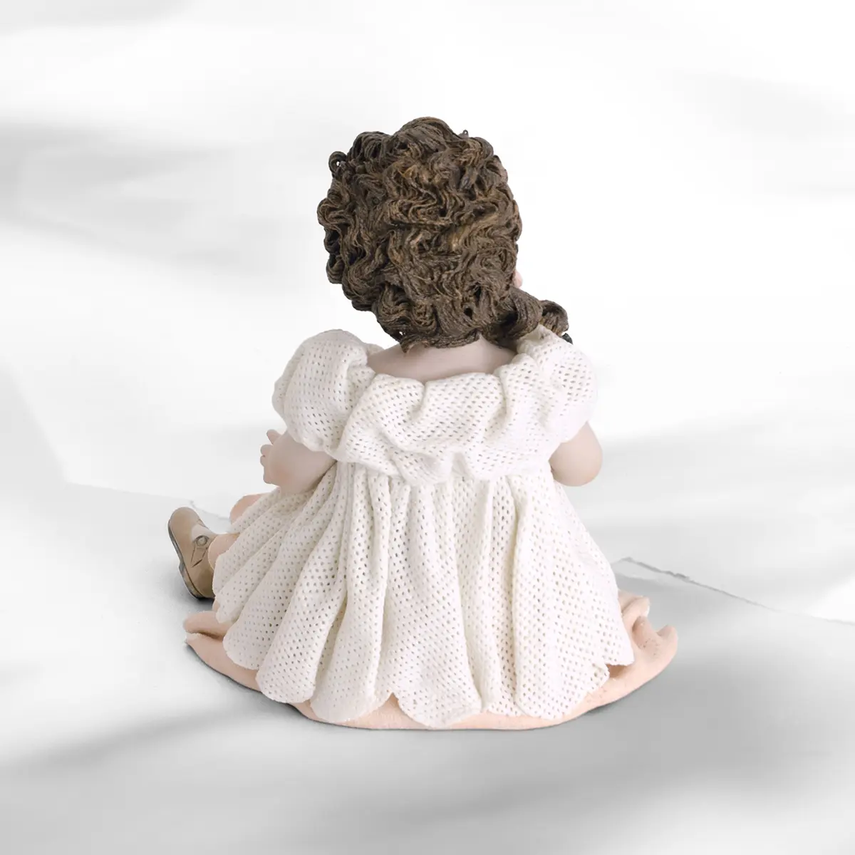 Statua in porcellana di ragazza seduta con abito in tulle, sottogonna rosa e fiorellini colorati in mano.