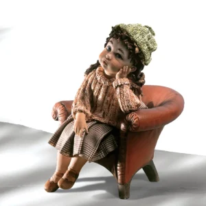 Statua in porcellana con bimba seduta su poltrona rossa, in abiti invernali e berretto verde.
