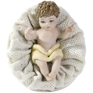 Tre statue in porcellana di Gesù Bambino steso in culla con cuscino in tulle, di diverse dimensioni.