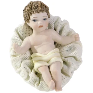 Tre figure in porcellana di Gesù Bambino steso in culla con panno crema e cuscino in tulle.