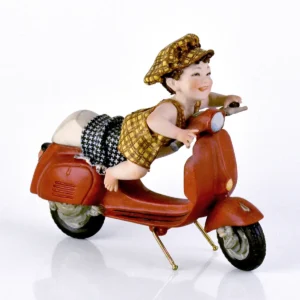 Statua in porcellana con bimbo in salopette e berretto giallo e marrone sulla Vespa rossa.