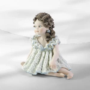 Statua in porcellana di bimba seduta in abito in pizzo bianco e azzurro, bavero a volants e coda con rosellina azzurra.