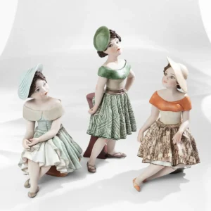 Statua in porcellana Maggie con gonna verde e bianca, bustino beige e cappellino fascinator, accanto a un tavolino.