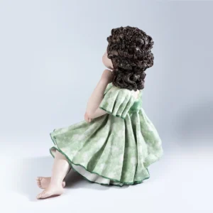 Statua in porcellana di ragazza seduta su uno sgabello, con abito verde tè e bordi verde smeraldo.