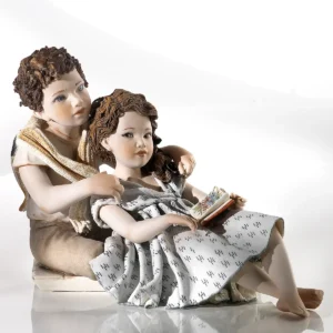 Statua in porcellana di ragazzo e ragazza stesi: lei in abito azzurro con libro, lui la abbraccia.