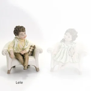 Statua in porcellana Lele: bimbo seduto su poltroncina bianca con maglioncino panna, pantaloni marroni e sciarpa verde.