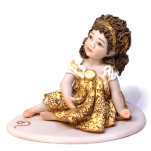 Statua mini in porcellana del Leone di Sibania con abito oro e ocra in pizzo, fascia dorata e base rossa.