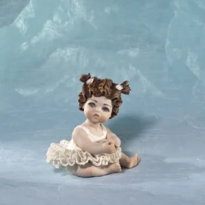 Statua in porcellana di bimba ballerina in tutù di pizzo, seduta a terra con due codine corte e fiocchetti bianchi.