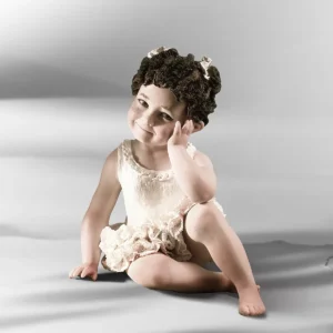 Statua in porcellana di bimba ballerina in tutù di pizzo, seduta a terra con gomito sul ginocchio e due chignon alti.