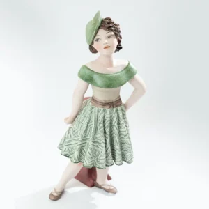 Statua in porcellana di Maggie con gonna verde e bianca, bustino beige e cappellino fascinator appoggiata a un tavolino.