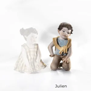 Statua in porcellana Julien con bimbo in ginocchio, t-shirt azzurra, maglioncino giallo sulle spalle e pantaloni marroni.