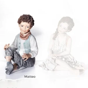 Statua in porcellana di Matteo, ragazzo seduto a terra con gilet verde Tiffany, camicia bianca e bandana pesca.