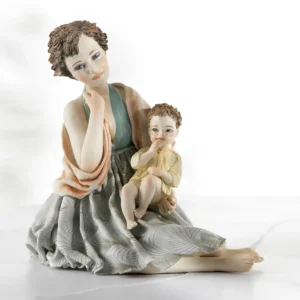 Statua in porcellana con mamma in abito azzurro e scialle salmone che tiene in braccio il suo bimbo in camiciola gialla.