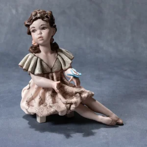 Statua in porcellana Michela in posa da ballerina con abito svolazzante e farfalla azzurra sulla mano.