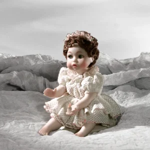 Statua in porcellana di bimba in abito di tulle bordato di rosa, con coroncina e candela in mano.