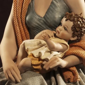 Statua in porcellana raffigurante una mamma in abito tortora e scialle salmone che tiene in braccio il suo bimbo.