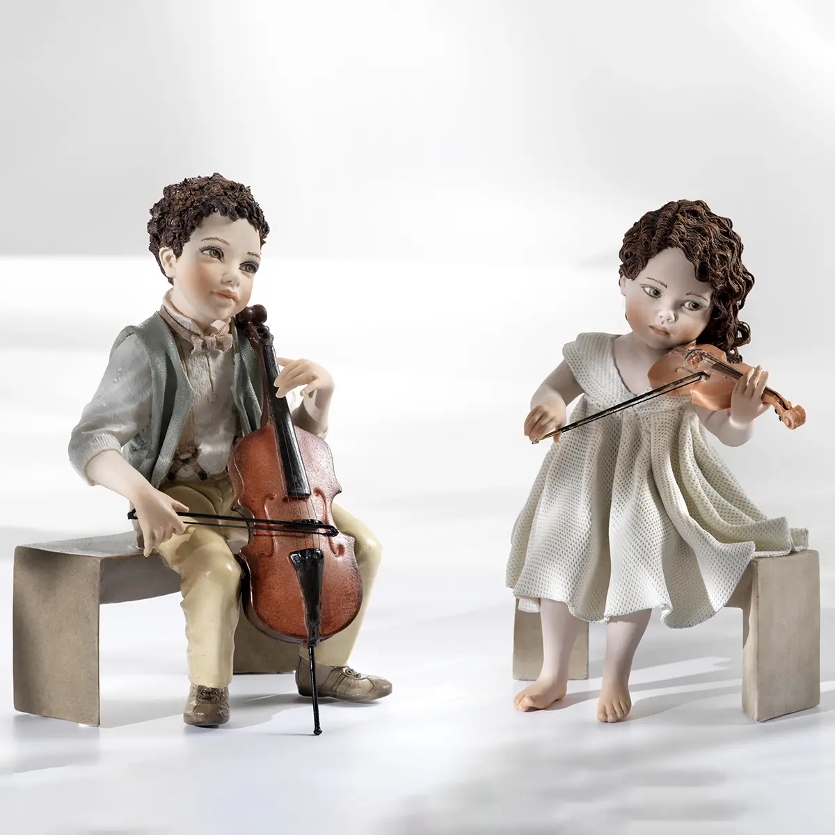 Statua in porcellana di ragazza con abito in tulle che suona il violino seduta su panca marmorizzata.