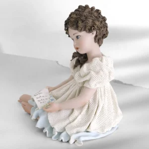 Statua in porcellana di ragazza seduta con abito in tulle bianco e sottogonna azzurra, con una lettera in mano.
