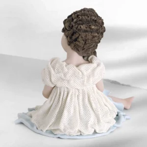 Statua in porcellana con ragazza seduta, abito in tulle bianco con dettagli azzurri e lettera in mano.