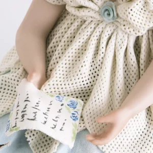 Statua in porcellana di ragazza seduta con abito bianco e azzurro in tulle e lettera in mano.