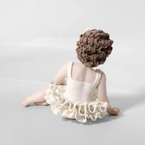 Statua in porcellana di bimba ballerina in tutù di pizzo, seduta a terra con fiocco bianco nei capelli.