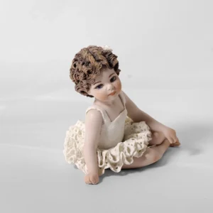 Statua in porcellana di bimba ballerina in tutù di pizzo, seduta a terra con le gambe di lato e fiocco bianco.