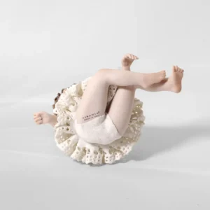 Statua in porcellana di bimba ballerina in tutù di pizzo, seduta a terra con fiocco bianco di lato nei capelli.