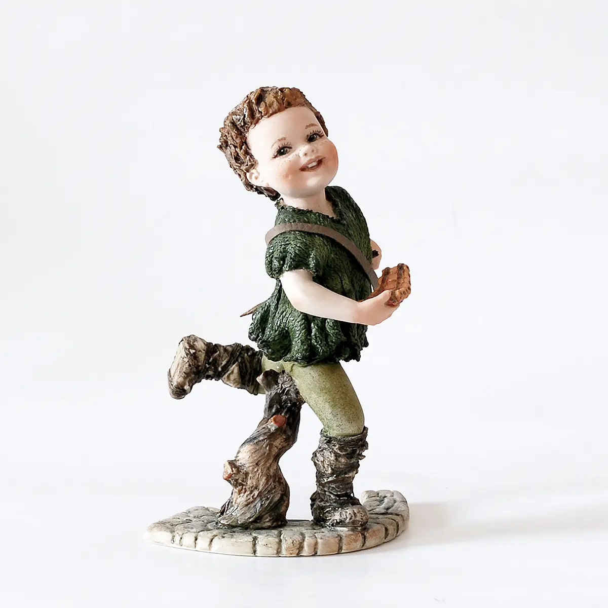 Statua in porcellana di Peter Pan con casacca verde bosco, spadino al fianco e flauto di bambù.