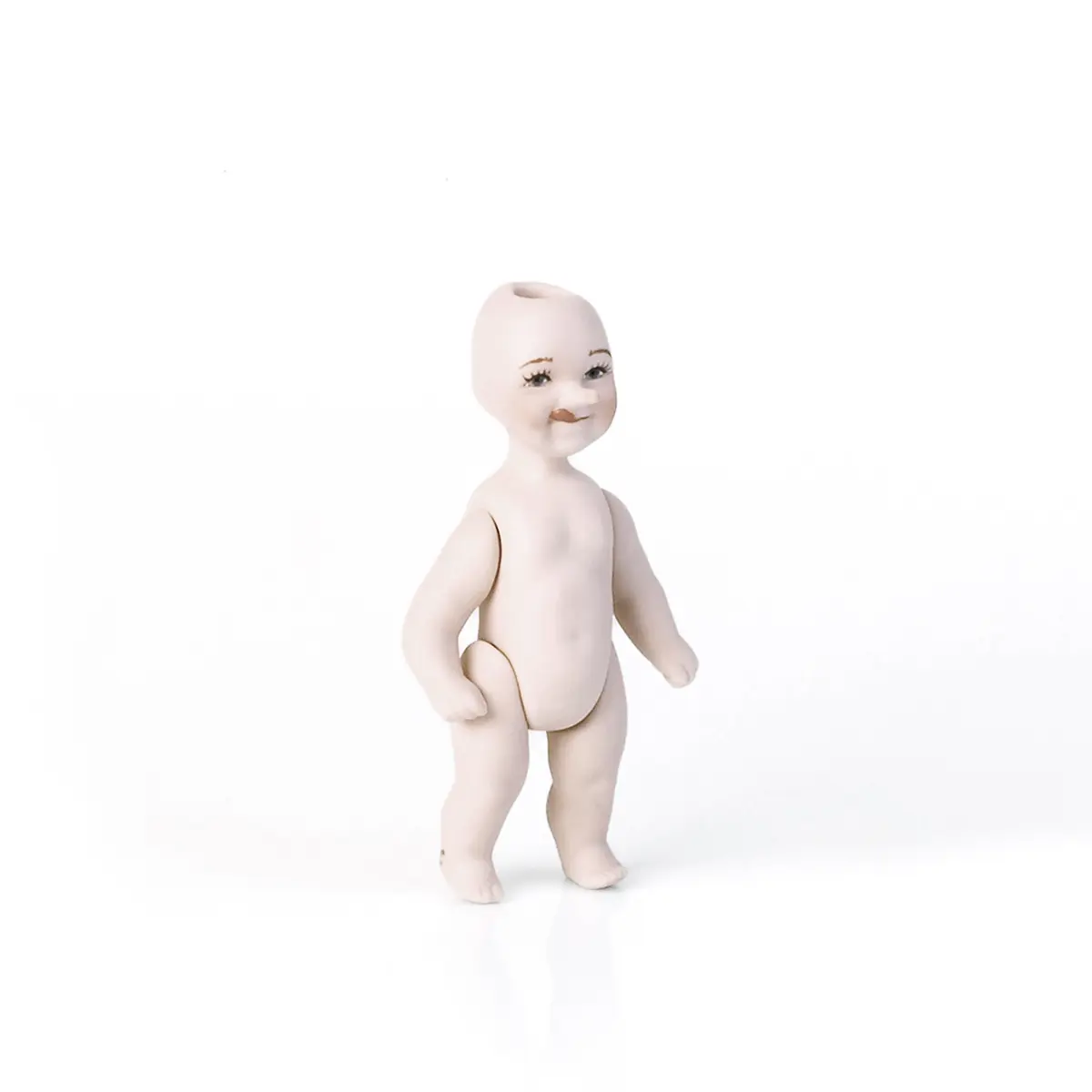 Bambolina in porcellana biscuit raffigurante un piccolo Pinocchio con linguetta di fuori e naso lungo.