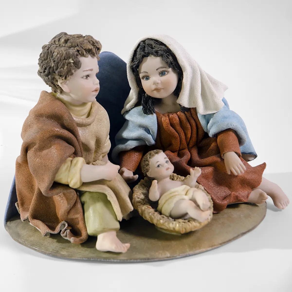 Presepe in porcellana con la Sacra Famiglia: Madonna in azzurro e rosso, San Giuseppe e Bambin Gesù sulla mangiatoia.