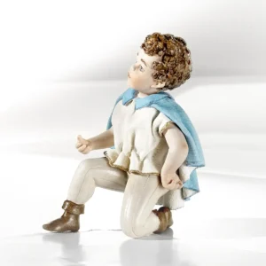 Statua in porcellana del Principe Azzurro in ginocchio, con casacca bianca e mantello azzurro.