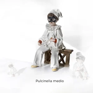 Statua in porcellana di Pulcinella seduto su una staccionata con abito bianco, maschera nera e cornetto rosso portafortuna.