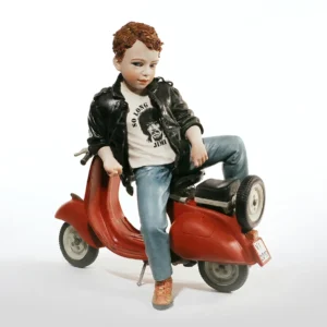 Statua in porcellana di un ragazzo in giacca di pelle nera e jeans seduto su una Vespa rossa.